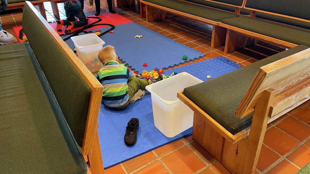 Barn som leker med Duplo i kirkerommet i Rossabø kirke
